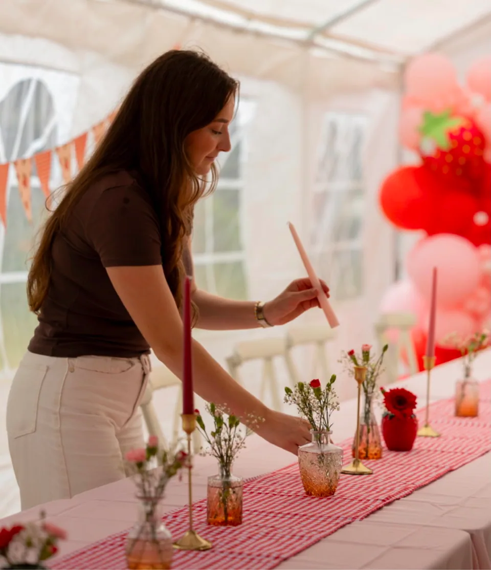 Dionne zet een kaars recht op een gedekte feesttafel in een feesttent