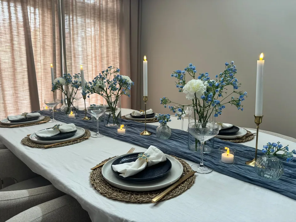 Tafelstyling in blauwe tinten met een gaasloper, blauwe bloemen en kaarsen