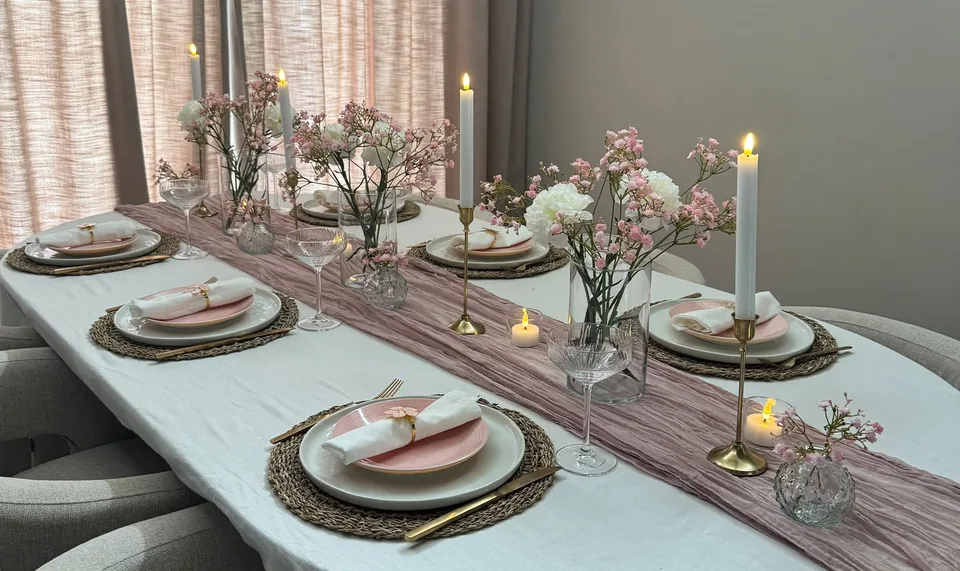 Tafelstyling in zachtroze tinten met bloemen, kaarsen en gouden bestek